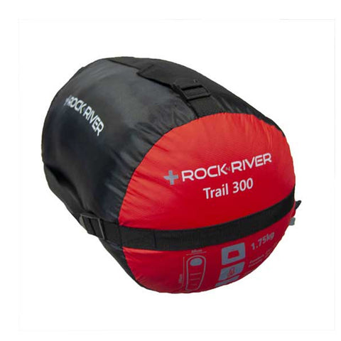 A black and red camping sleeping bag is displayed. It is rolled tightly for storage, featuring a label indicating "Rock River Trail 300" and a weight of 1.75kg.