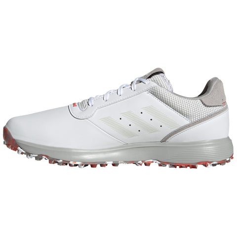 A white athletic shoe with gray accents is positioned sideways displaying its smooth surface and textured mesh details while the sole features visible spikes designed for grip on grass or turf.
