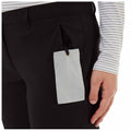 Black pants with a side pocket are shown with a light gray tag hanging from them The tag has the text CRAGHOPPERS Glass Wipe visible and a hand is positioned near the pants