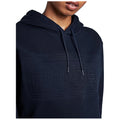 A person wears a dark hooded sweatshirt featuring an embossed text that reads HUNTER while slightly smiling against a plain white background.