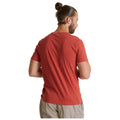 A red t-shirt displays a graphic design featuring the words "GO EXPLORE OUTDOOR CALLING" along with an illustration of stone structures. This shirt appears casual and suitable for outdoor activities.