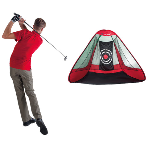 A golfer wearing a red shirt and gray pants swings a club aiming at a red and black practice net with a target design set in an isolated environment.