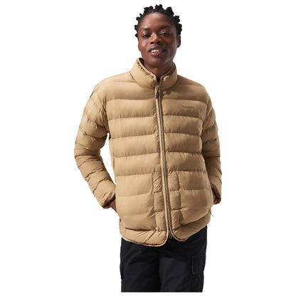 A person is standing and smiling while wearing a tan puffer jacket with a high collar, showcasing a casual and warm style in a neutral background.