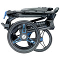 A black folding wheelchair with blue accents rests in a compact position showcasing its wheels and frame designed for easy transportation and storage in various environments.