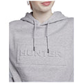 A person is wearing a gray hoodie with an embossed logo reading HUNTER on the front while slightly smiling under natural lighting. The focus is on the hoodie and the person's face.