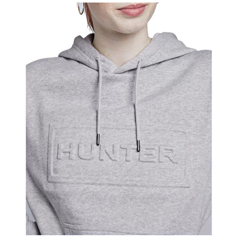 A person is wearing a gray hoodie with an embossed logo reading HUNTER on the front while slightly smiling under natural lighting. The focus is on the hoodie and the person's face.