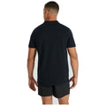A man in a black polo shirt and shorts stands with his back facing the viewer against a light background, showcasing a casual outfit.