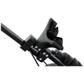 A black plastic device with adjustable straps is attached to a metal frame It appears to be a mounting bracket possibly for securing equipment in place in a mechanical setup
