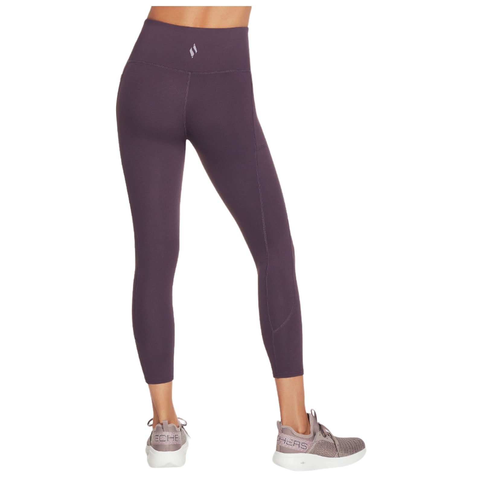 Leggings are worn with a high waistband and a fitted silhouette highlighting the legs they are paired with athletic shoes in a neutral, indoor setting.