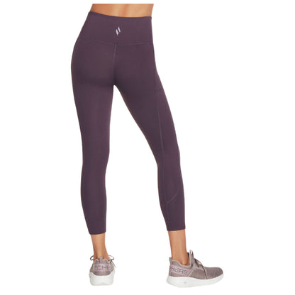 Leggings are worn with a high waistband and a fitted silhouette highlighting the legs they are paired with athletic shoes in a neutral, indoor setting.