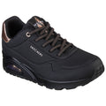 A black sneaker with a textured surface features bronze accents and laces. It showcases a cushioned sole and is designed for comfort and casual wear. The brand name is visible on the side.