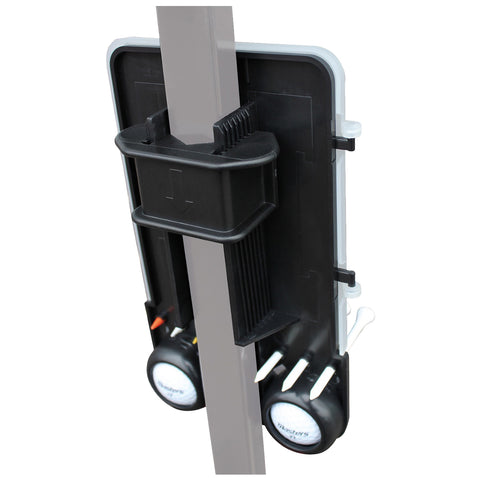A black and gray golf accessory stores golf balls and tees with a vertical attachment for easy access on a pole near a golf course or practice area.