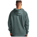 A person wearing a green hoodie stands with their back to the viewer in a neutral space, suggesting a casual and relaxed atmosphere. The hoodie features a hood and a simple, comfortable design.