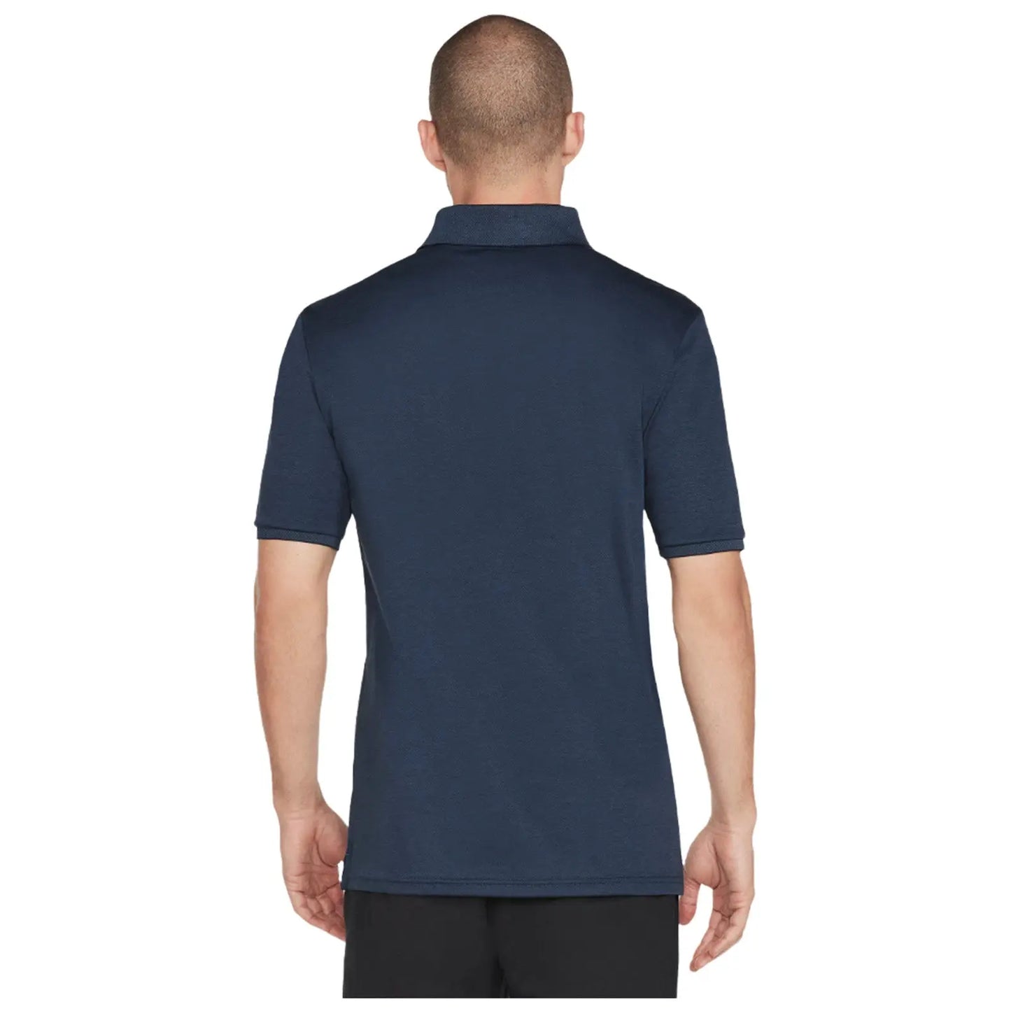 A man is wearing a navy blue polo shirt while facing away. The shirt has short sleeves and a classic collar. He appears in a neutral indoor setting.