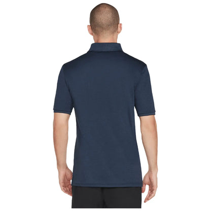 A man is wearing a navy blue polo shirt while facing away. The shirt has short sleeves and a classic collar. He appears in a neutral indoor setting.