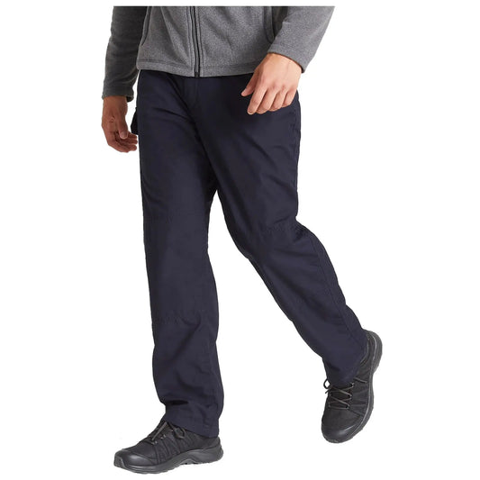 A person is walking in dark pants and a gray zippered jacket wearing black shoes in a neutral, indoor setting. The focus is on their midsection and lower body.