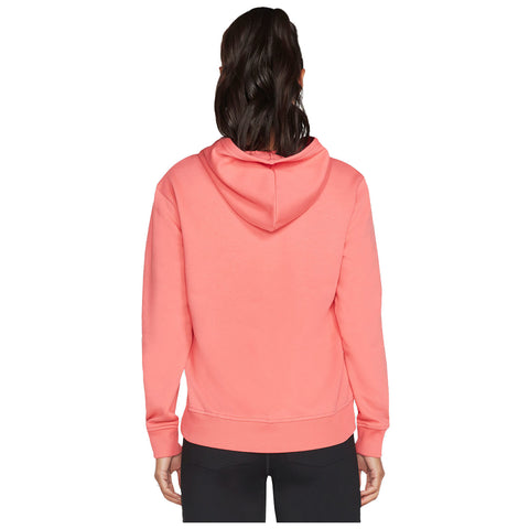 A person is wearing a coral pink hoodie with a hood pulled up and is facing away from the viewer in a neutral background and black pants