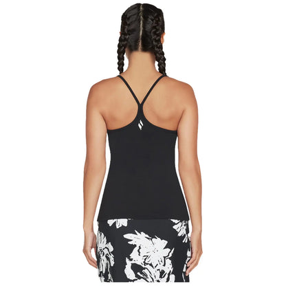 A person is wearing a black sleeveless top with a racerback design and is facing away. The lower half features a patterned skirt with white floral designs.
