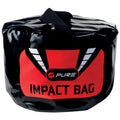 A round black impact bag with a bright red and black design is positioned upright. It features a carrying handle on top and prominently displays the words "PURE IMPACT BAG."