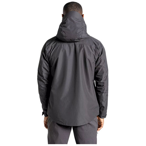 A person wearing a black jacket stands with their back facing the viewer in a neutral background, highlighting the jacket's features and the individual's posture.