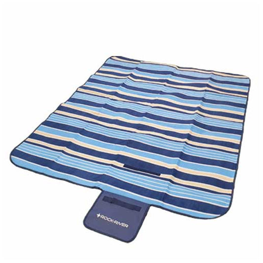 A blue and beige striped picnic blanket is laid out flat on a surface with a carrying handle at one end indicating ease of transport for outdoor use.