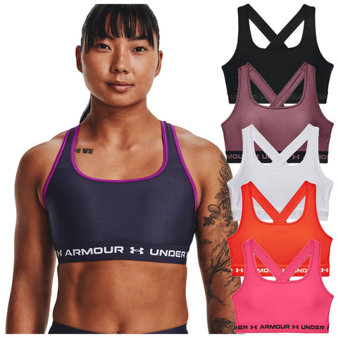 A woman with a tattoo wears a dark sports bra with purple accents while several other colored sports bras are displayed beside her in a bright and neutral background.