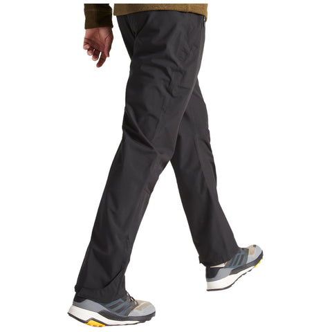 A person is walking in black pants and gray athletic shoes, showcasing a casual outdoor or active wear style in a neutral background.