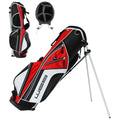 A golf bag stands upright on metal legs featuring a red black and white design with multiple zippered pockets for storing golf gear and an open top for club access
