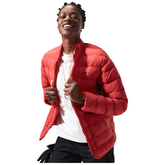 A person is smiling and holding the sides of a bright red puffer jacket that is unzipped. They are wearing a white shirt underneath and are set against a plain white background.