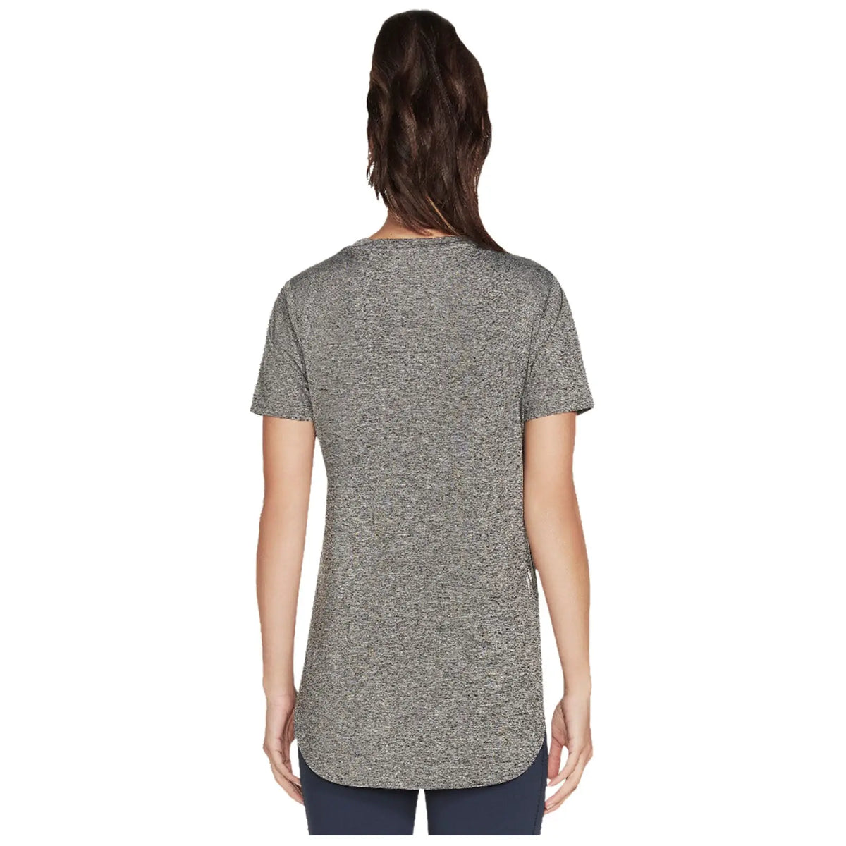 A person is standing with their back facing the viewer wearing a loose-fitting gray short-sleeve shirt that has a rounded hem in a neutral background.