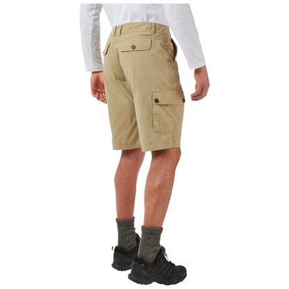 A person is standing with their back facing the viewer wearing khaki cargo shorts and black shoes paired with dark green socks in a neutral background setting.