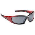 Sunglasses with a red and black frame are positioned at an angle showcasing dark lenses designed to block sunlight in an outdoor setting.