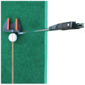 A golf putter is poised above a white golf ball with an orange line, ready to strike it on a green turf surface, indicating a practice or training setting.