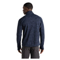 A person wearing a navy blue long-sleeve top stands with their back turned, showing the textured fabric. The setting is neutral and unadorned, focusing on the clothing.