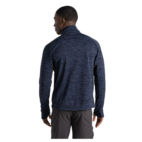 A person wearing a navy blue long-sleeve top stands with their back turned, showing the textured fabric. The setting is neutral and unadorned, focusing on the clothing.