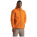 A man is standing confidently wearing an orange jacket with a hood and a logo on the left side while posing against a plain white background.