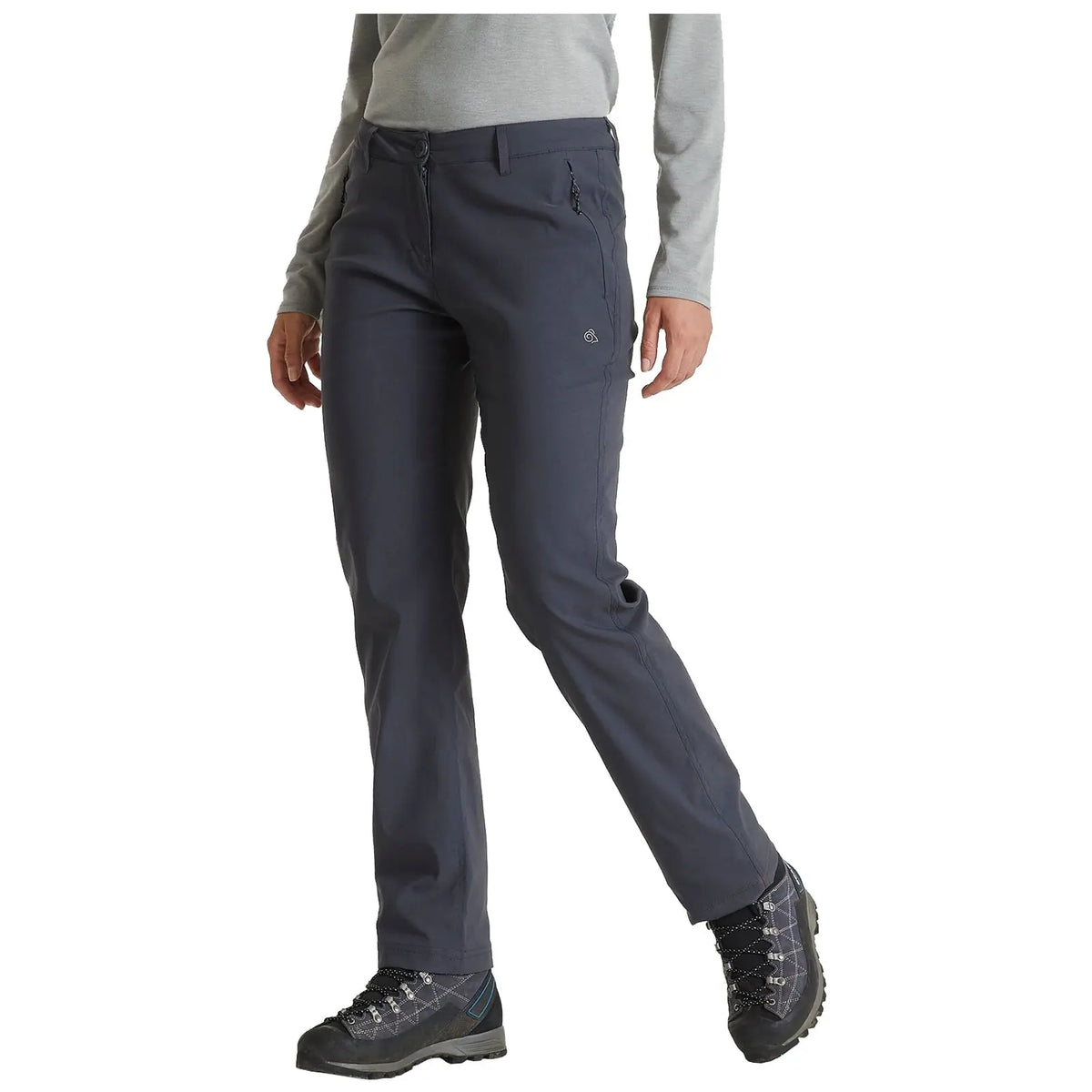 A person is wearing dark gray hiking pants and sturdy boots while standing with one leg slightly forward in a casual outdoor setting. The individual has a neutral expression and is dressed in a long-sleeved light gray top.