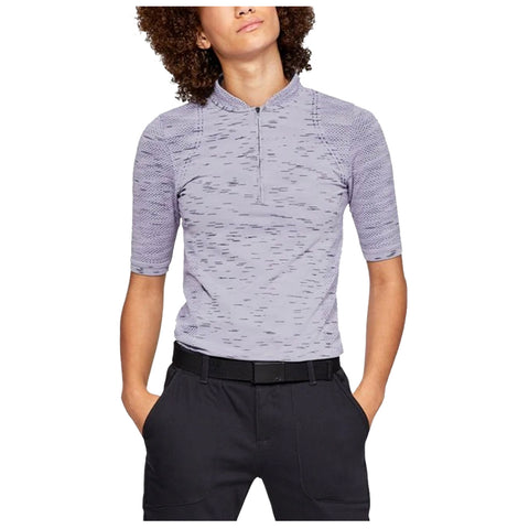 A person stands confidently wearing a short-sleeved, light purple athletic shirt with a zippered collar and black pants, hands in pockets, against a plain white background.