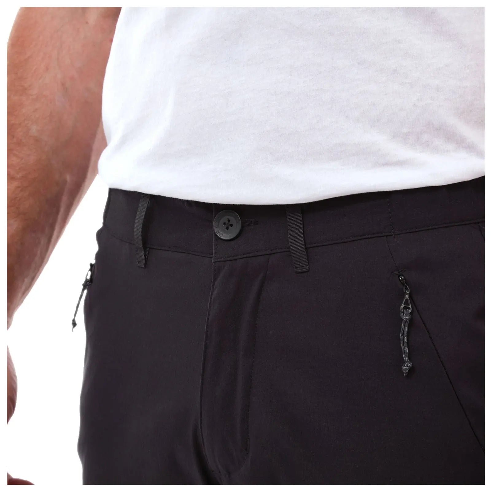 Black pants feature a buttoned waistband and a zipper pocket on the side while a man's arm, partially visible, suggests casual wear in a neutral indoor setting.