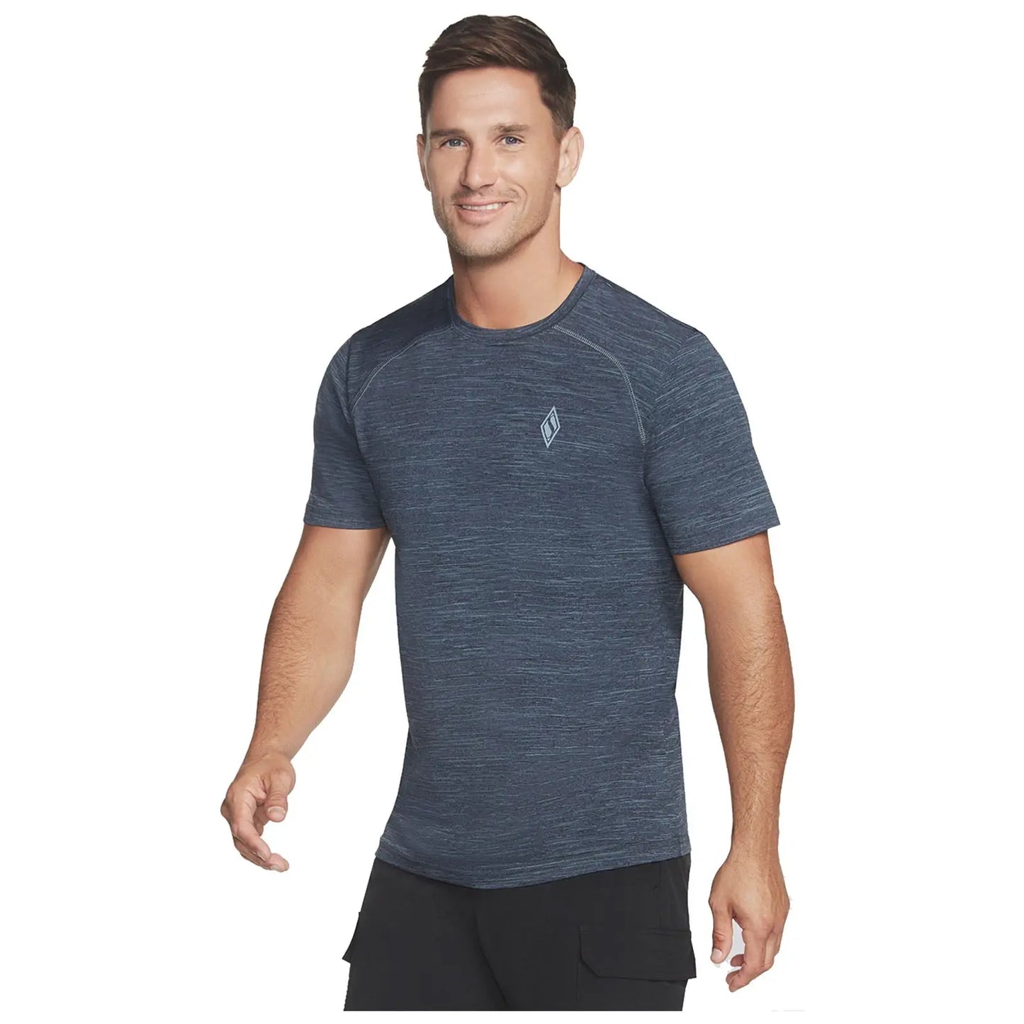 A man wearing a dark blue athletic t-shirt smiles while walking towards the viewer in a casual setting. He appears fit and relaxed.