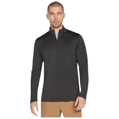 A man wearing a dark grey zip-up long sleeve shirt stands upright showcasing a confident expression against a plain white background highlighting the garment details and fit.