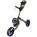 A golf push cart is positioned upright with a handle and large blue wheels. It is designed for transporting golf clubs on a course, featuring a sturdy frame and foot brake.