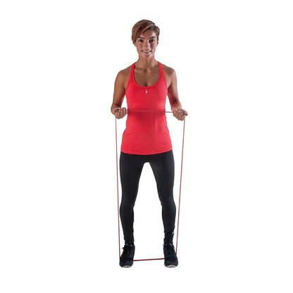 A woman stands upright holding a resistance band with both hands the band is stretched between her hands showing an exercise posture the background is plain white