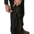 A person is fastening a zipper on black pants with one hand while the other hand holds the fabric, indicating the pants are being adjusted or secured in place.
