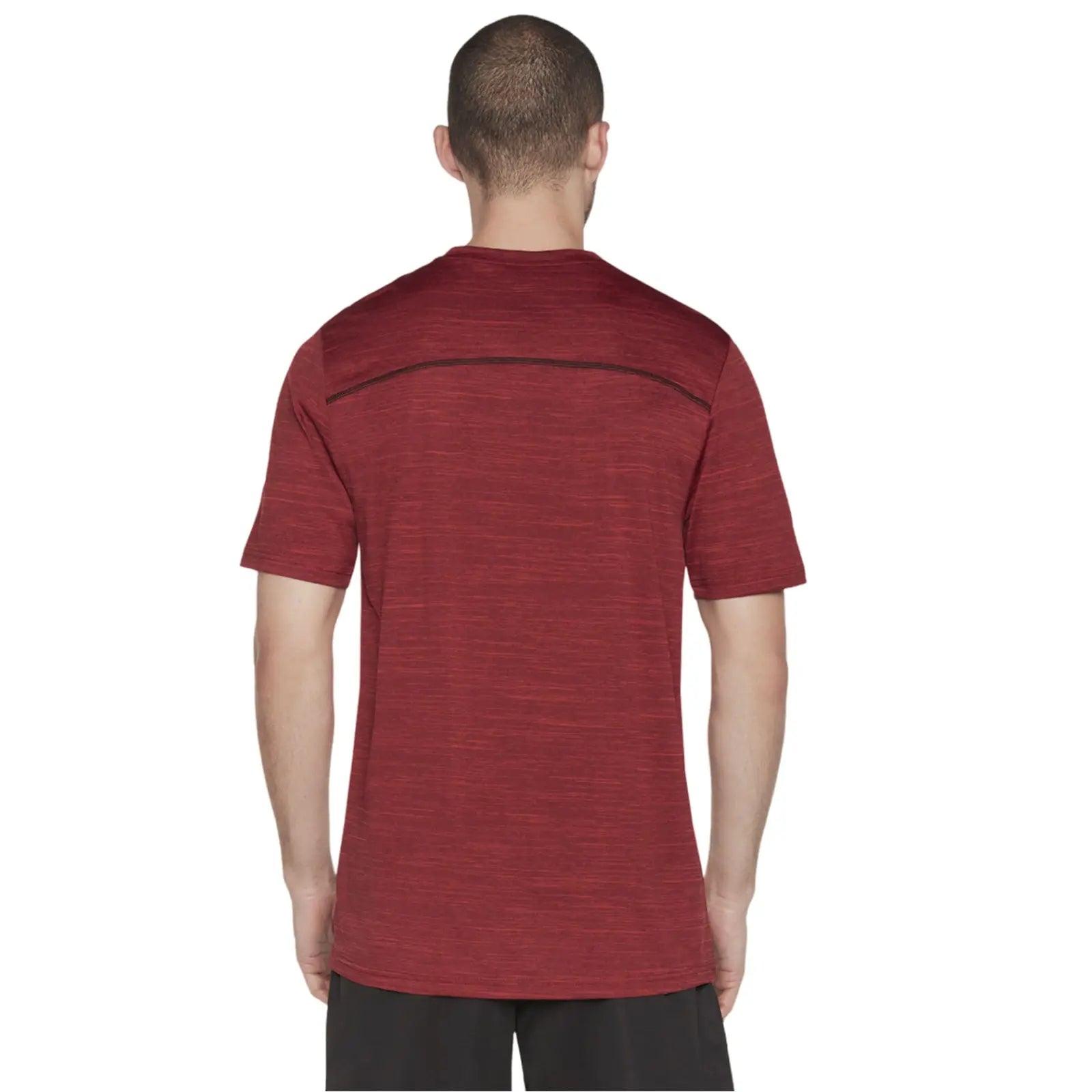 A person stands with their back facing the viewer wearing a red athletic shirt with short sleeves and a rounded neckline in a neutral background suggesting a simple indoor setting.